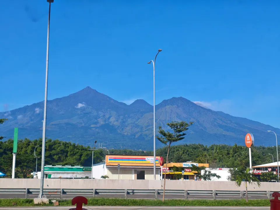 An Indomaret at a Malang toll road rest stop, with mountains and clear blue skies in the background.