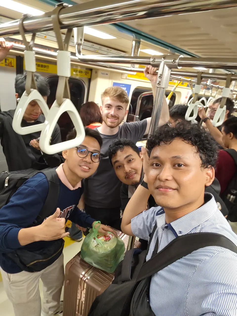 A group of friends taking a selfie aboard a crowded Taipei metro train.